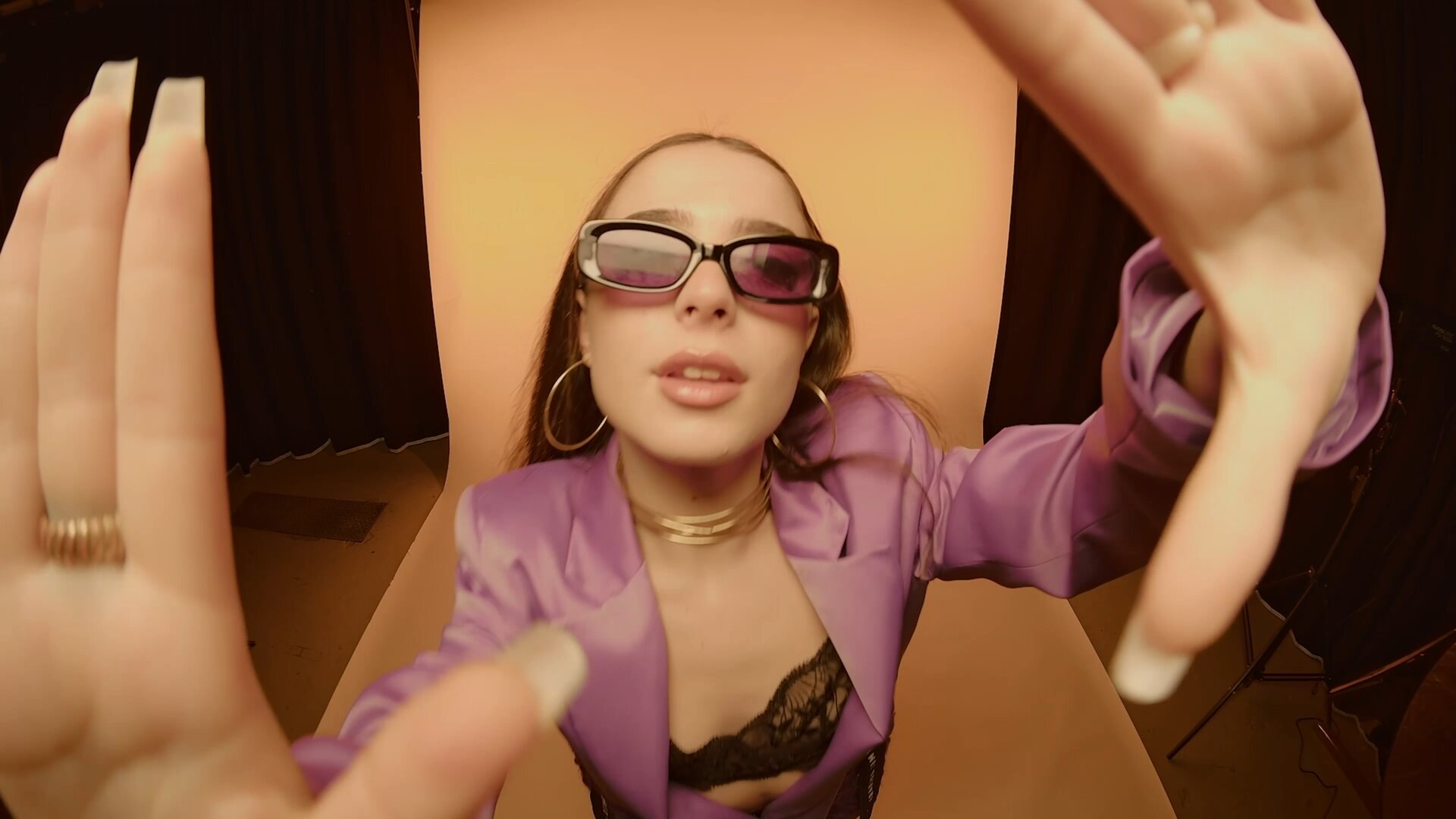 Low-angle shot of model in purple jacket reaching toward the lens